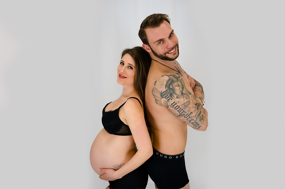 Donna Bellini Fotostudio fuer Babybauch Fotoshooting Munchen Schwangere Frau mit ihrem Mann posieren fuer Babybauch Fotos