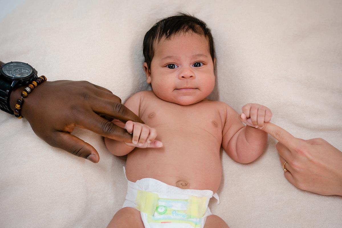 Neugeborenes-Baby-haelt-den-Finger-der-Mutter-unde-Vater-beim-Neugeborenen-Fotoshooting-im-Donna-Bellini-Fotostudio
