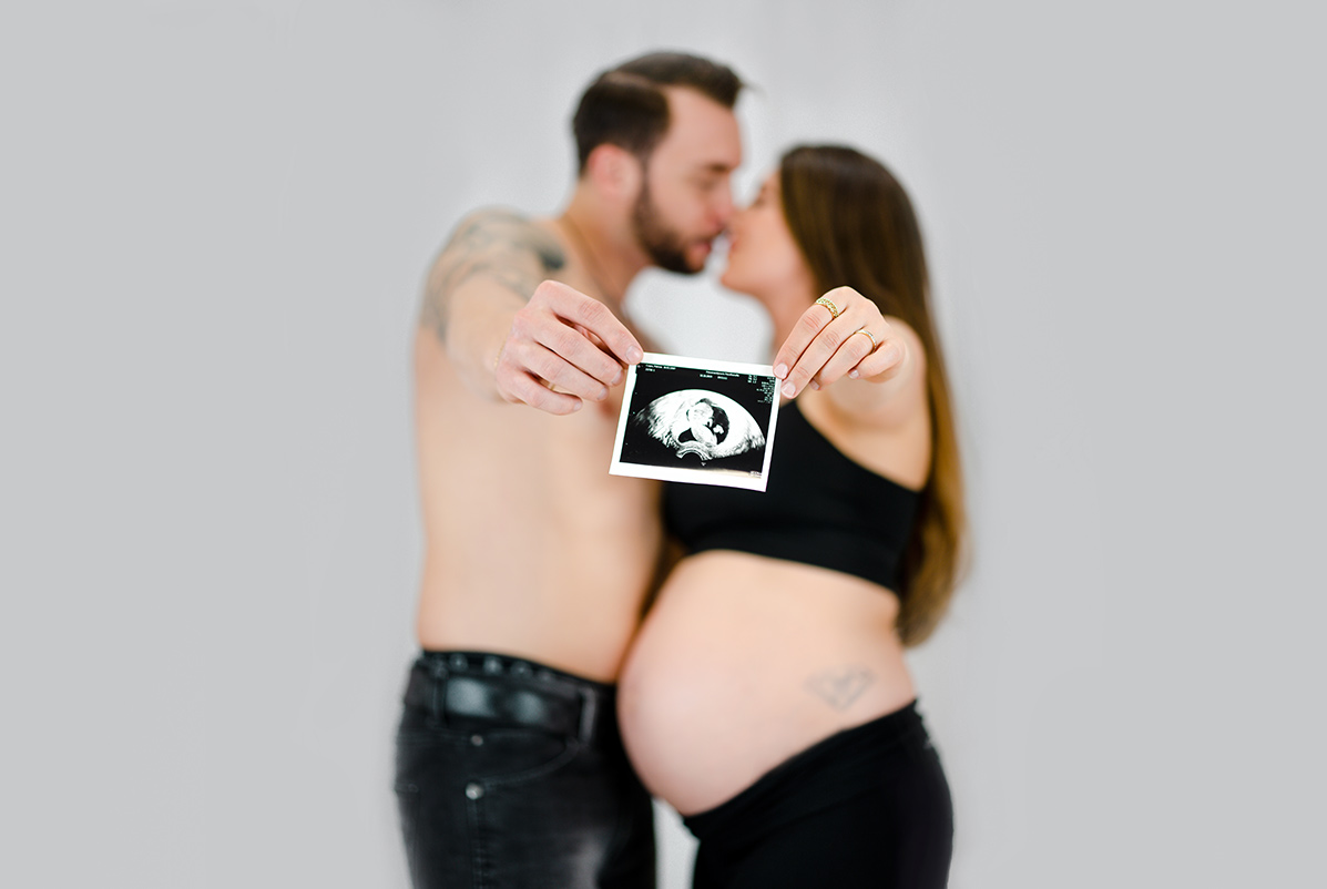 Schwangere Frau mit Mann posieren fuer Babybauch Fotos Donna Bellini Fotostudio fuer Babybauch Fotoshooting Munchen