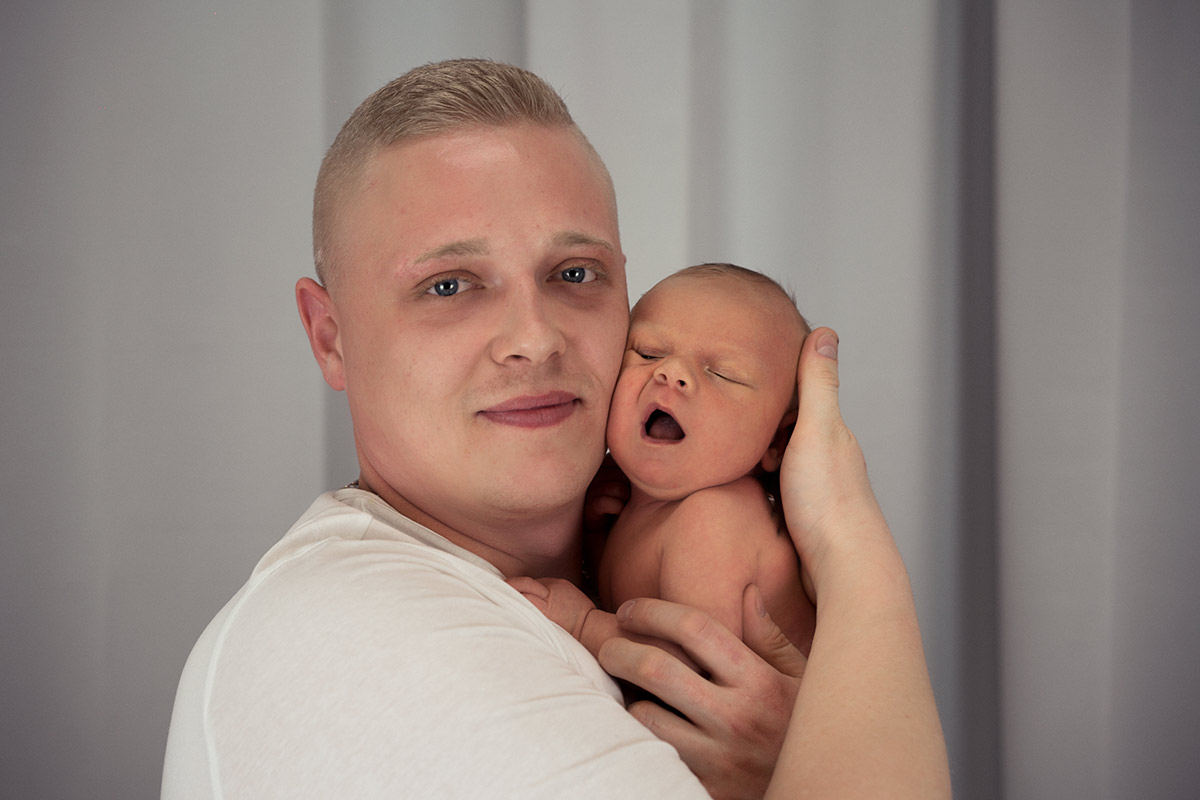 Vater-haelt-neugeborenes-Baby-in-den-Armen-im-Donna-Ballini-Fotostudio-in-Muenchen