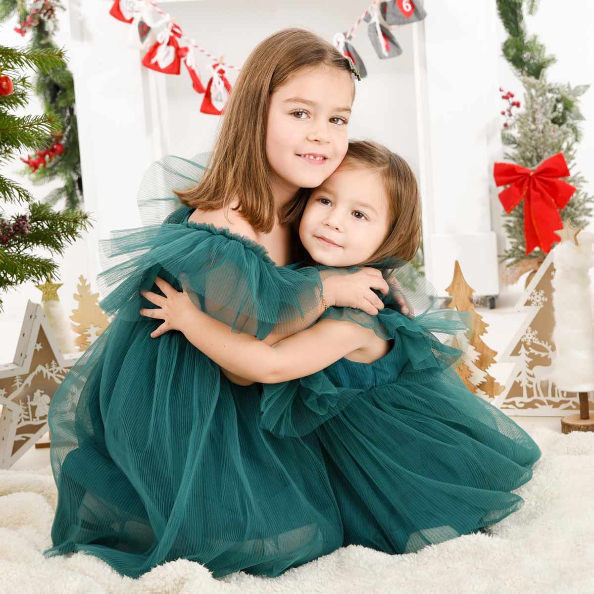 Weihnachts-Fotoshooting-Zwei-Schwestern-in-gruenen-Kleidern-die-sich-umarmen